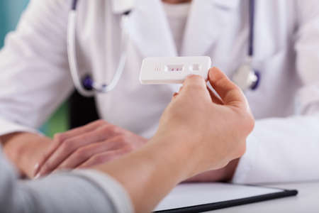 Close-up of female hands with positive pregnancy test at doctor's office