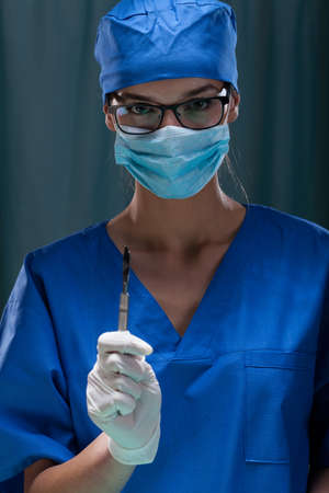 Portrait of a female surgeon holding surgical scalpel, verticalの写真素材
