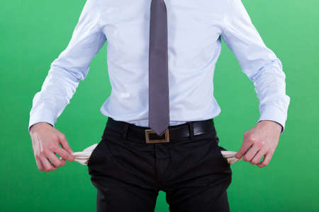Businessman with empty pockets, isolated on green backgroundの写真素材