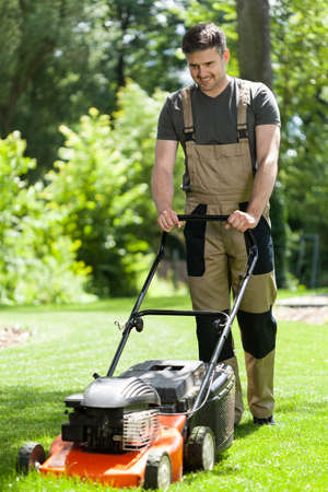 Man in work overalls mowing lawn, verticalの写真素材