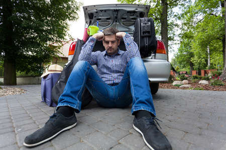 Upset man and car full of luggage bags before the family vacationの写真素材