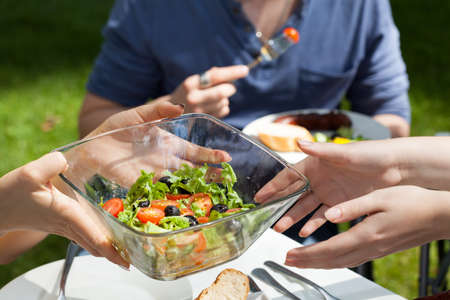 Host serving healthy fresh salad on garden party 
