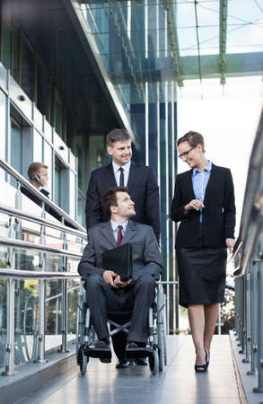 Young businessman on wheelchair and his co-workers, verticalの写真素材