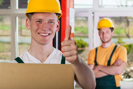 Smiling warehouseman in hardhat showing thumbs up sign