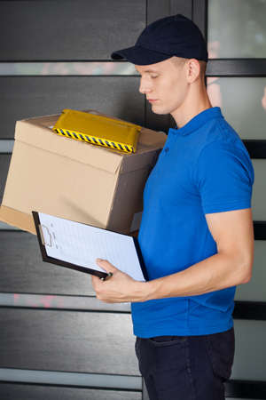 Young delivery man in blue uniform during workの写真素材