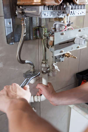Close-up of a hands using wrench to repair the gas water heaterの写真素材