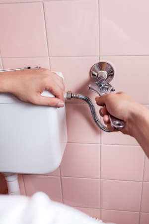 Close-up of a hands repairing toilet, verticalの写真素材
