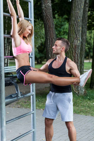 Man helps woman with training in a park