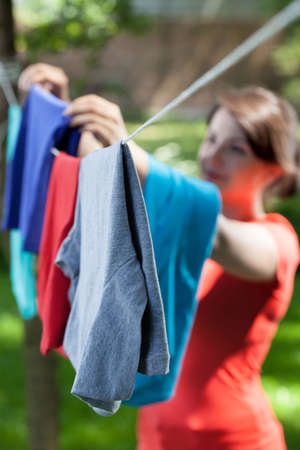 Woman hanging clothes on laundry line in garden, verticalの写真素材