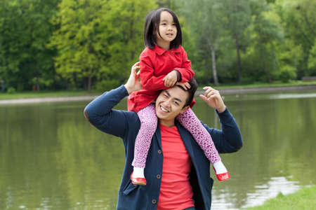 Asian dad and daughter by the lake