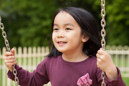 Asian girl swinging on a swing, horizontalの写真素材