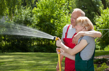 Couple in love watering grass in a gardenの写真素材