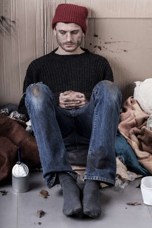 Sad and dirty homeless man sitting on the ground 