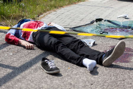 Caution tape and dead man lying on the street, horizontalの写真素材
