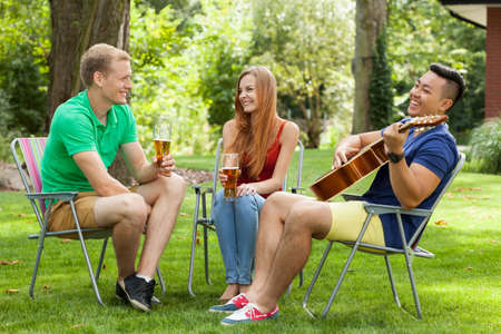 Asian man playing the guitar in a gardenの写真素材