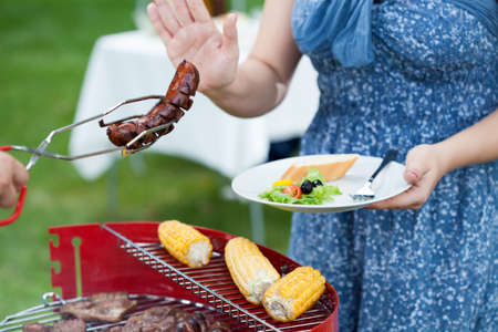 Woman on a diet during barbecue, horizontalの写真素材