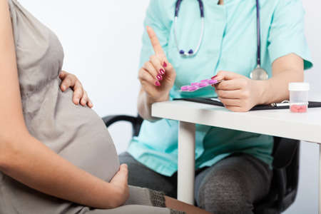 Gynecologist talking with pregnant woman in the officeの写真素材