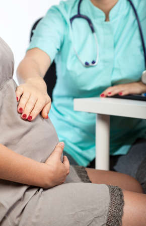 View of doctor touching pregnant woman's bellyの写真素材