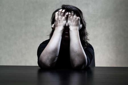 Sorrowfull young woman hiding her face in hands