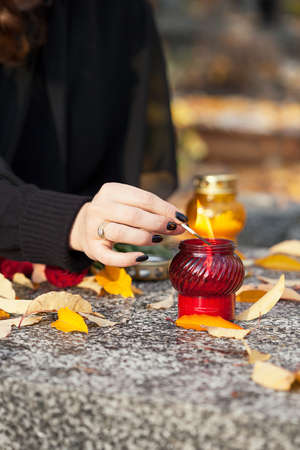 Young widow lighting a candle on the husband graveの写真素材
