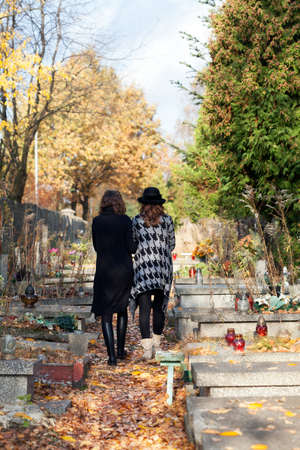 Sisters in mourning walking at the cemetery after mother death