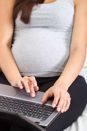 Close-up of pregnant woman and laptopの写真素材