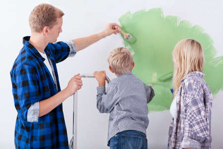 Back view of a family painting interior wall of homeの写真素材