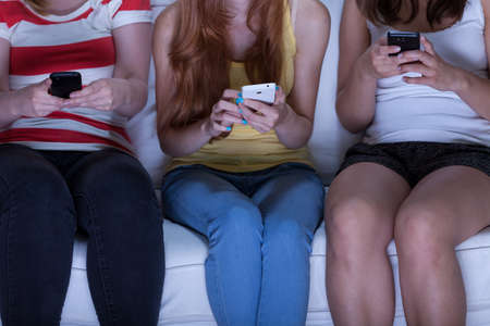 Friend sitting on couch and sending text messagesの写真素材
