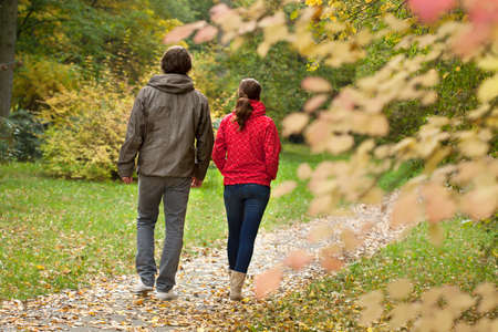 Happy couple resting and walking in autumn forest の写真素材