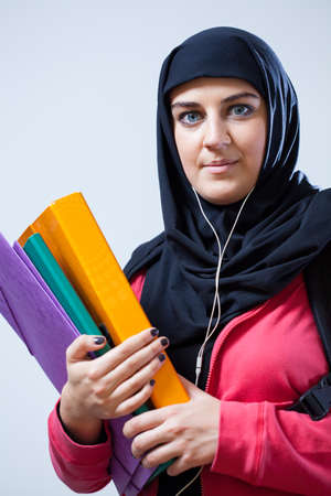 Vertical view of Arab female student holding briefcases