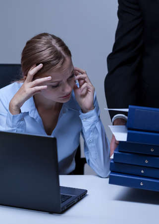 Young attracitve overworked employee at her officeの写真素材