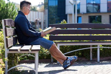 Asian man reading a book on student campの写真素材
