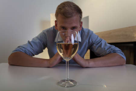 Addicted young man with glass of wineの写真素材