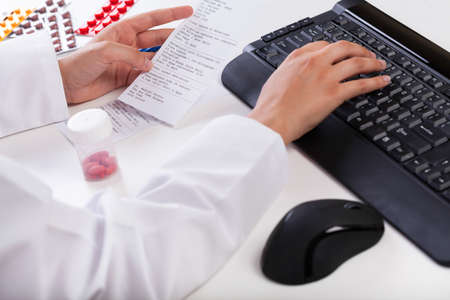 Pharmacist typing on keyboard and realizing rx paper