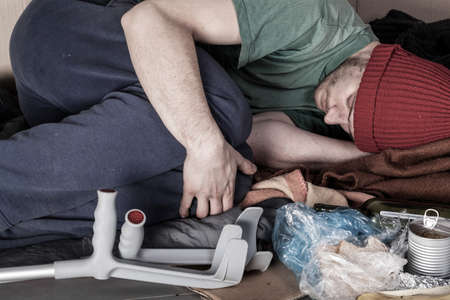 Ill homeless man lying curled up on the street