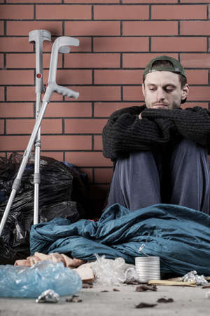 Ill homeless young man sitting on the ground