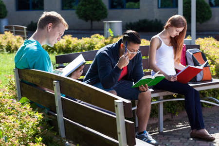 Young people sitting on the bench and studying to the examの写真素材
