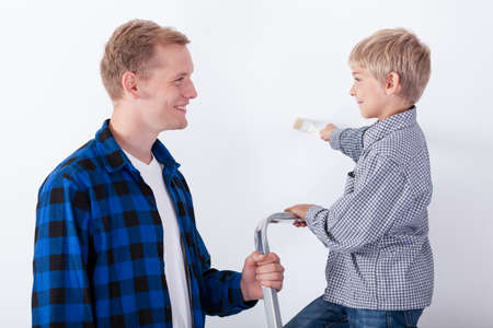 Father learning his son how to paint a wall, horizontalの写真素材