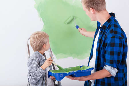Dad and son painting wall in child's roomの写真素材
