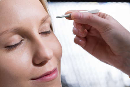 Horizontal view of woman during eyebrow depilationの写真素材