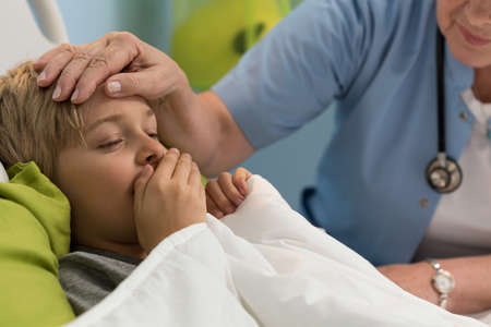 Close-up of coughing toddler lying in hospital bedの写真素材