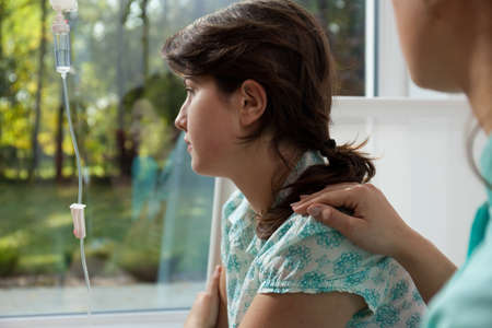 Young female physician cheering up her young sick patientの写真素材