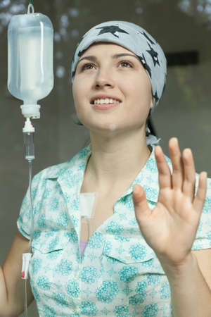 Photo of pretty smiling cancer girl connceted to chemotherapyの写真素材