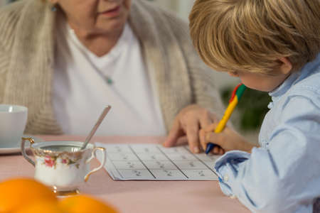 Blonde schoolchild doing his homework from mathの写真素材
