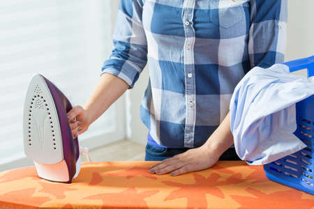 Horizontal view of woman during clothes ironingの写真素材