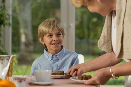 Horizontal view of grandmother serving homemade cakeの写真素材
