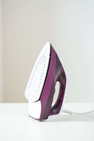 Purple iron on white ironing board, verticalの写真素材