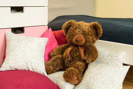 Teddy bear lying on bed of little girlの写真素材