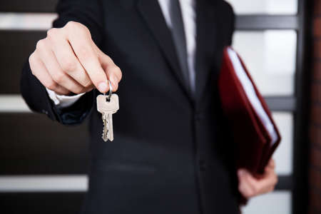 Close-up of house keys held by house agentの写真素材