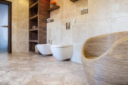 Beige and bright bathroom with wicker chairの写真素材